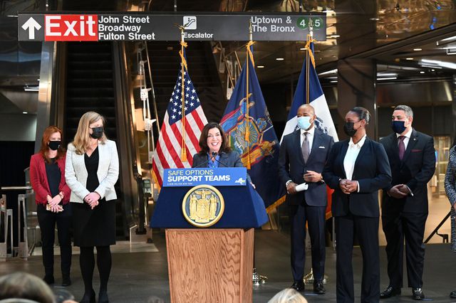Governor Kathy Hochul a lectern in the Fulton Street subway station, surrounded by officials including Mayor Eric Adams and NYPD Commissioner Keechant Sewell